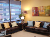 photo sherman oaks office suite 1101, two brown sofas with pillows, multi colored wall
 painting
