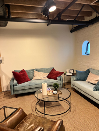photo glendale office, two arched windows, glass coffee table, grey sofa, tan leather chair