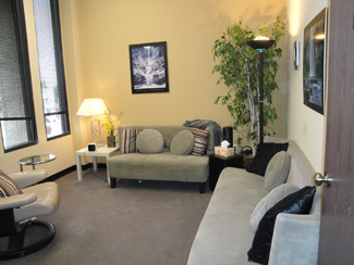 photo tarzana office space suite 33, two grey sofas with pillows, art on wall, white chair, greenery